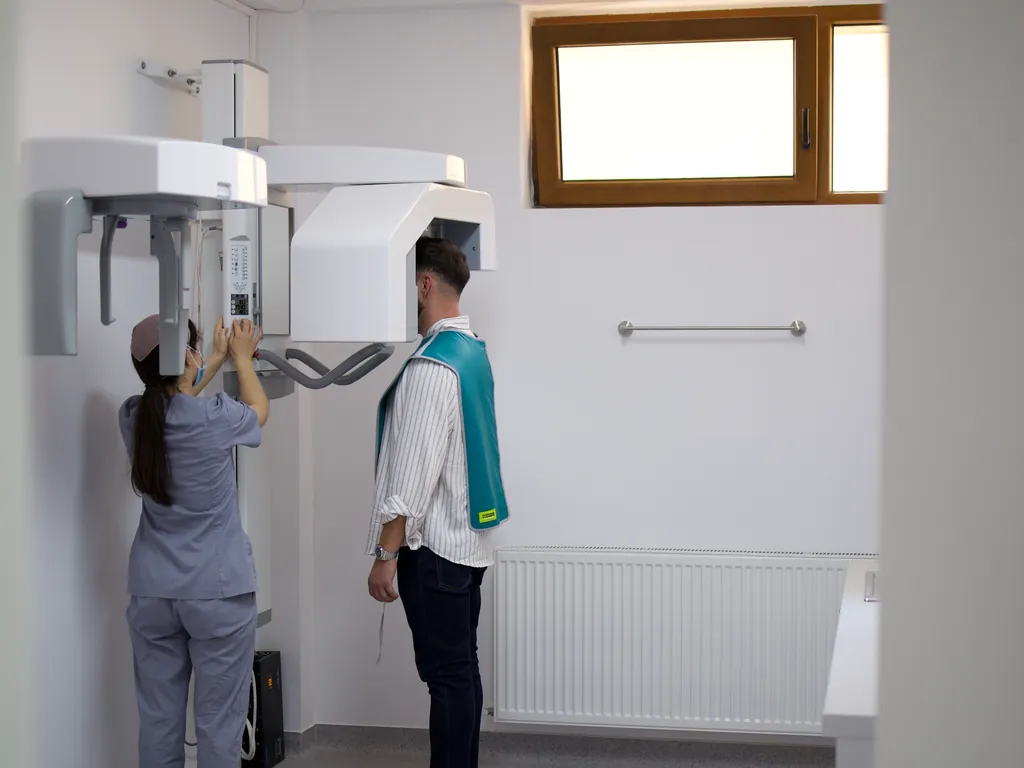 Pacient poziționat în aparatul de radiografie panoramică, în cabinetul de radiologie