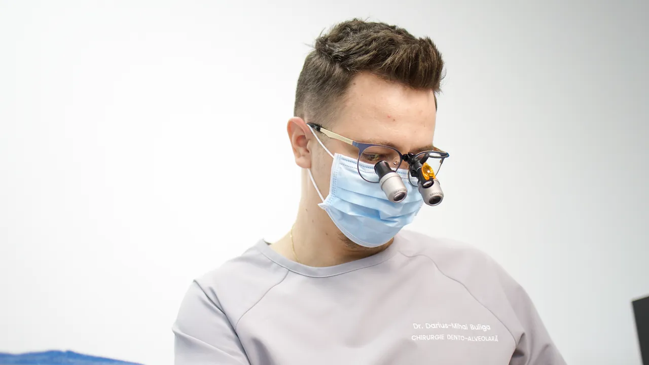Medic cu lupe de mărire și lampă frontală, în timpul unei intervenții