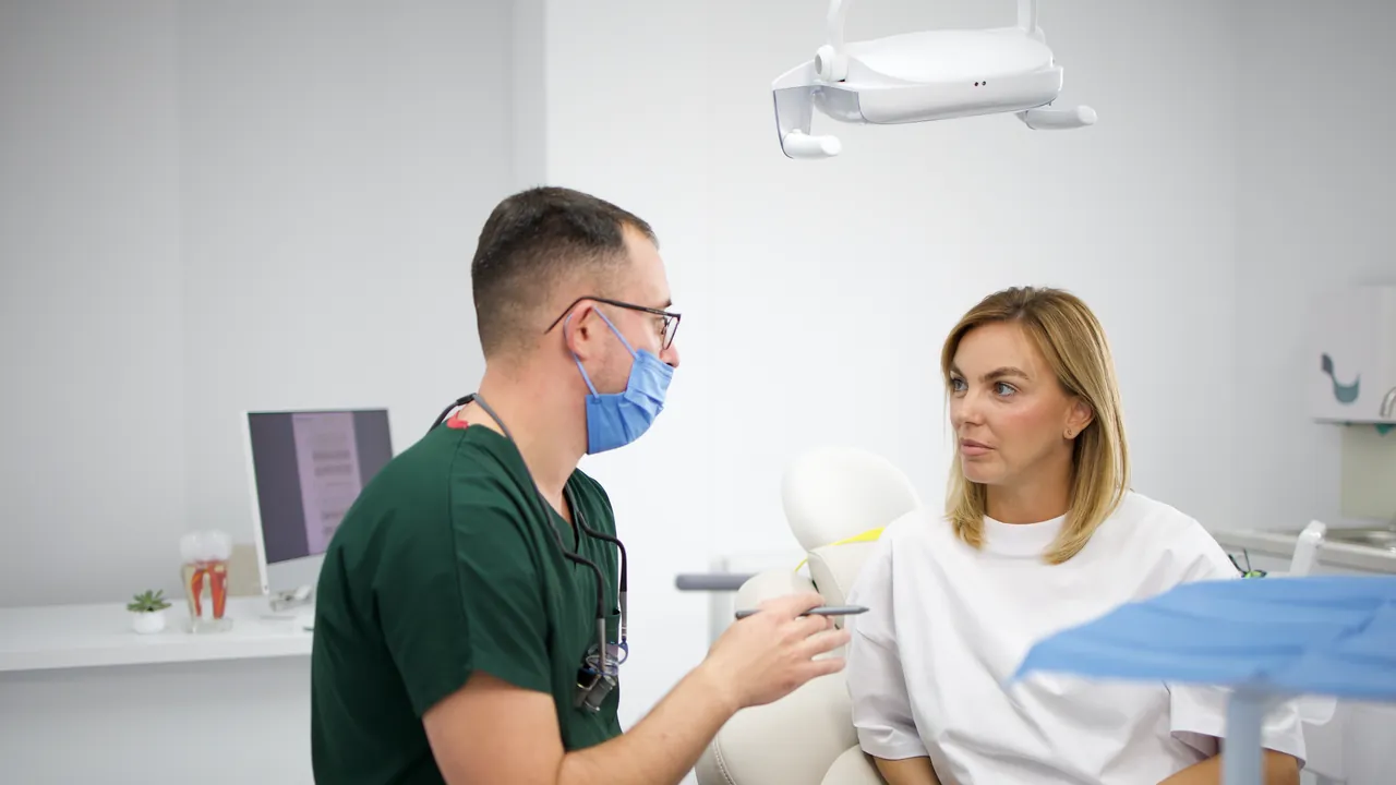 Medic stomatolog discutând cu o pacientă, în cabinet